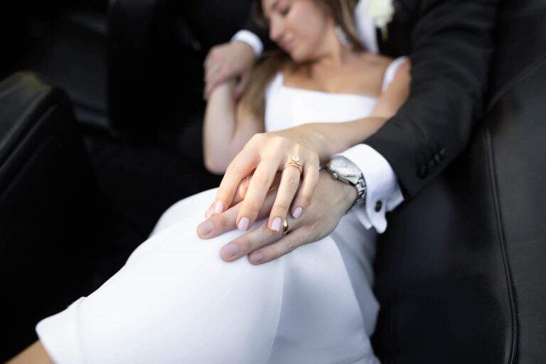 Close up of the engagement ring on the bride's hand on top of the groom's hand.