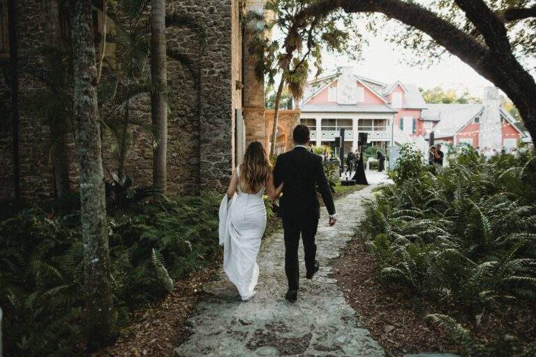 A bride and groom hand-in-hand as they walk together to their wedding reception.
