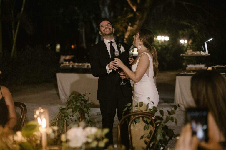 A bride and groom laughing and holding a microphone at their wedding reception.