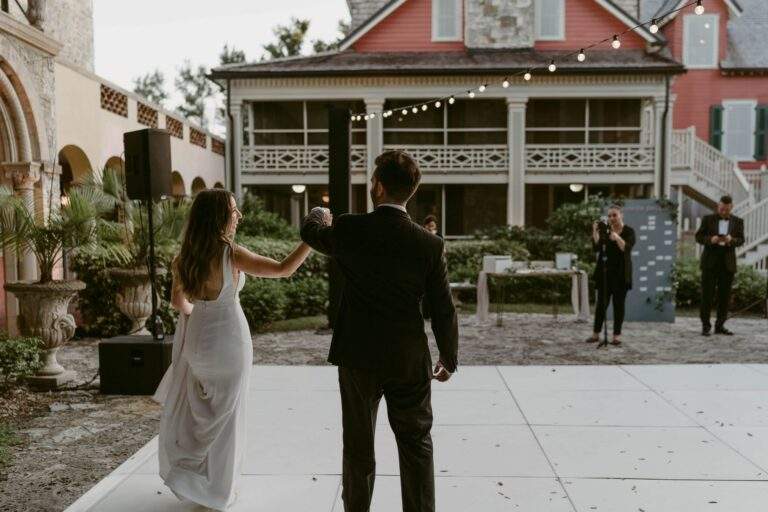 A bride and groom hand-in-hand as they walk out onto the dance floor.