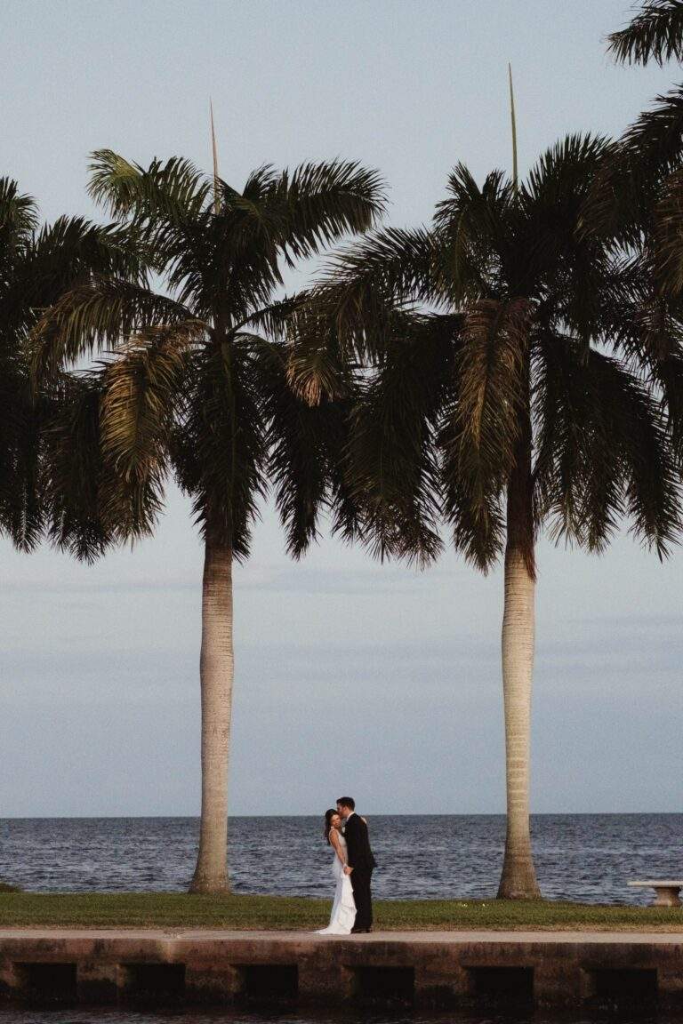 A faraway view of a bride and groom standing on the boat basin jetty at Deering Estate.