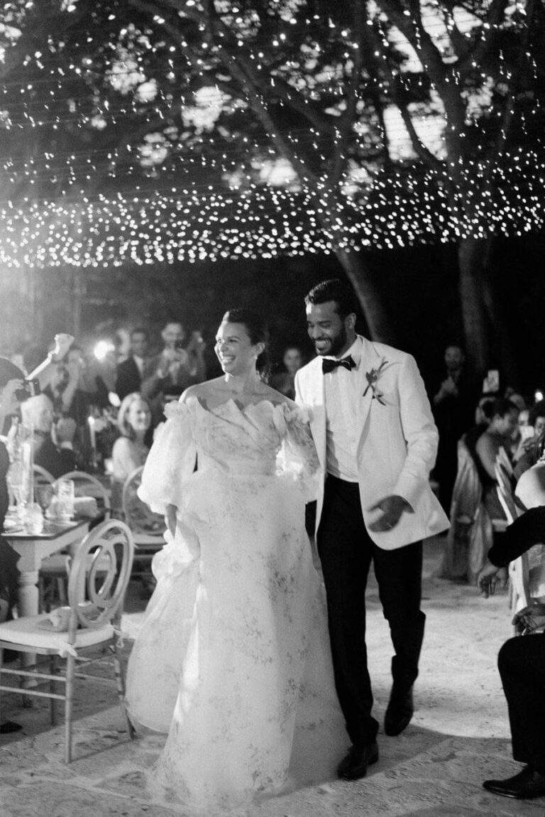 Couple entering the reception site at Deering Estate's Courtyard for the first time with guests in the background, edited in black and white