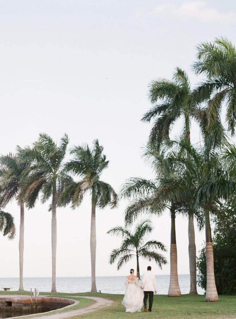 Couple at Deering Estate's Boat Basin walking towards the south finger with palm trees in the background