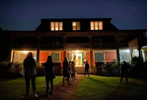 Eight people on a Deering Estate ghost tour at night in front of the Richmond Cottage.